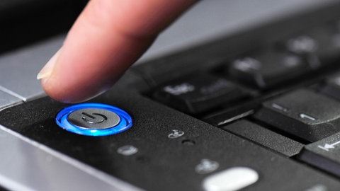 Finger am Powerknopf an einem Laptop