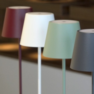Bunte Lampen stehen nebeneinander. Wand- und Tischleuchten mit Akku – kabellos und praktisch. Wie lange halten die LED-Lampen? Und kann man die Akkus wechseln, wenn sie hinüber sind?  
