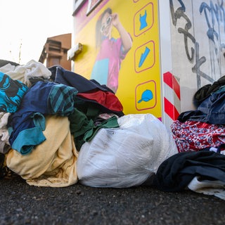 Gebrauchte Kleidungsstücke liegen vor einem Sammelcontainer für Altkleider (zu dpa: «Deutlich mehr Textilabfälle in Deutschland»)