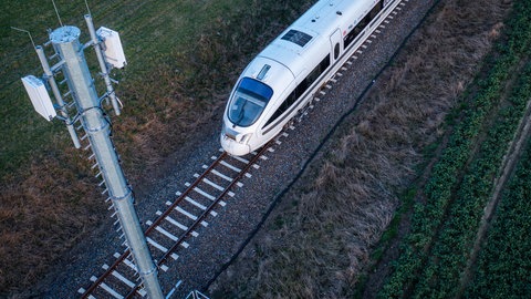 Ein Zug fährt an einem Mobilfunkmast vorbei