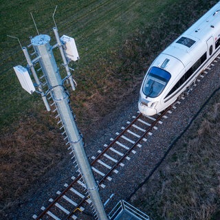 Ein Zug fährt an einem Mobilfunkmast vorbei