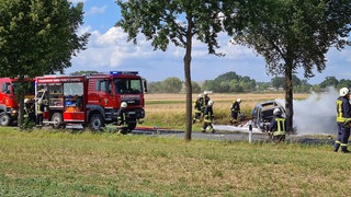 Feuerwehrleute löschen das Unfallwrack eines E-Autos. 