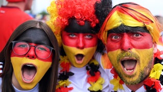 Fußballfans aus Deutschland sind in schwarz-rot-gold angezogen.