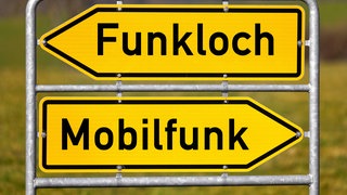 Ein Wegweiser zeigt auf einer Fotomontage zwei entgegengesetzte Richtungen mit den Begriffen FUNKLOCH und MOBILFUNK. Die Bundesnetzagentur verlängert die  Mobilfunkfrequenzen unter Auflagen. Die Mobilfunkanbieter müssen Funklöcher stopfen und den Empfang vor allem in ländlichen Regionen, an Autobahnen und Gleisen verbessern.Es soll auch ein Mindestgeschwindigkeit für Downloads geben.