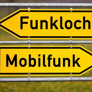 Ein Wegweiser zeigt auf einer Fotomontage zwei entgegengesetzte Richtungen mit den Begriffen FUNKLOCH und MOBILFUNK. Die Bundesnetzagentur verlängert die  Mobilfunkfrequenzen unter Auflagen. Die Mobilfunkanbieter müssen Funklöcher stopfen und den Empfang vor allem in ländlichen Regionen, an Autobahnen und Gleisen verbessern.Es soll auch ein Mindestgeschwindigkeit für Downloads geben.