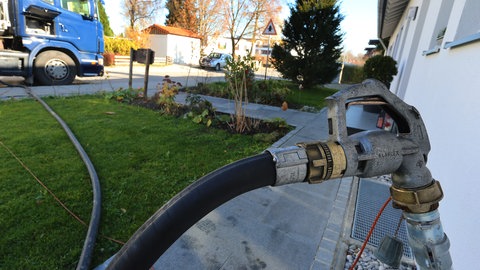 Vom Tanklaster führt ein Schlauch zu einer Zapfpistole, die im Rohr an einer Hauswand mündet. Wenn weniger Heizöl im Tank ist, als bezahlt wurde: Betrug bei der Lieferung? So stellen Sie sicher, dass bei der Heizöl-Lieferung vom Tankwagen bis in den Keller keine Fehler passieren.