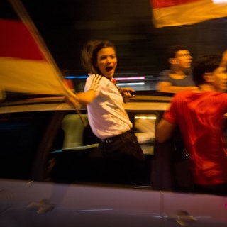 Drei Fußballfans bei einem Autokorso mit Deutschlandflaggen. Verbraucherrechte – was ist bei der Fußball-EM alles erlaubt?