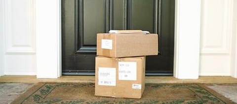 Vor einer Haustüre stehen ein Paket, das vom Paketdienst geliefert wurde. 