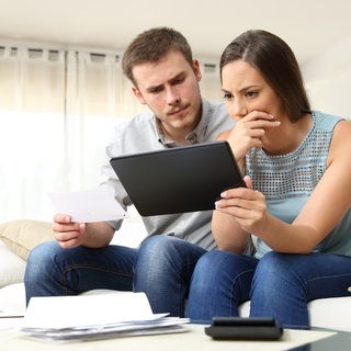 Mann und Frau grübeln über ihrem Tablet. Recht haben und bekommen sind oft verschiedene Dinge. Die Rechtsschutzversicherung soll vor Gericht helfen. Was kann sie vorschreiben? Und was tun, wenn der Versicherer kündigt?