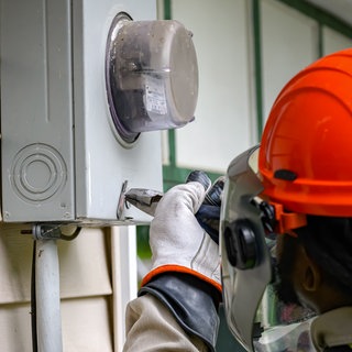 Handwerker schraubt an altem Stromzähler