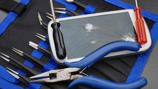 Ein Handy mit zerbrochenem Display und Werkzeug