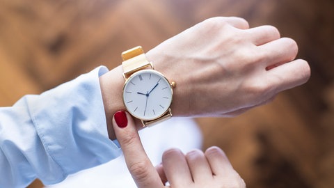 Man sieht die Linke Hand einer person die eine Uhr trägt. Das Bild ist aus dem Blickwinkel der Pesonen geschossen und es scheint als würde sie auf die Uhr gucken.