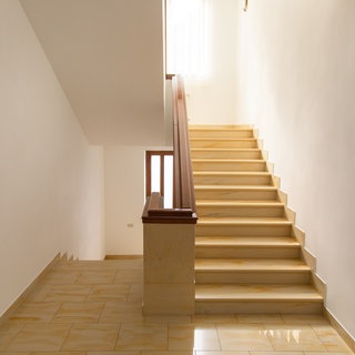 Ein Treppenhaus mit einer Treppe, welche nach unten und oben führt und zwei Hände, die einen Geldbeutel mit wenigen Münzen halten. Verpasste Widerrufsfrist: Nie installierter Treppenlift wird teuer.