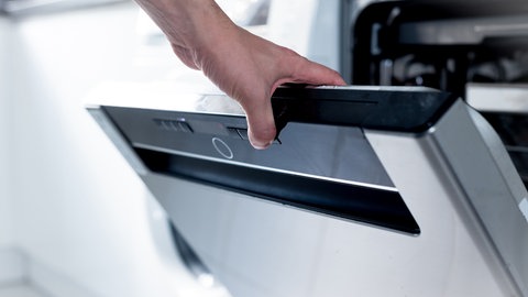 Mann öffnet Spülmaschine