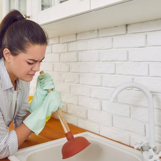 Frau versucht Abfluss wieder frei zu kriegen