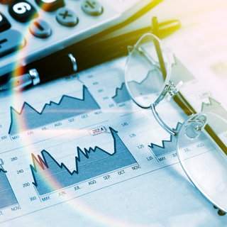 Aktienpapier, Taschenrechner und Brille liegen auf dem Tisch