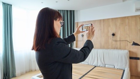 Frau fotografiert Mängel im Hotelzimmer