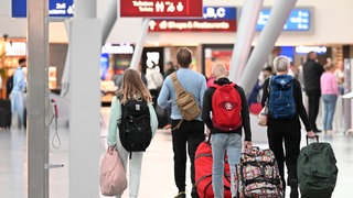 Menschen laufen mit Koffern auf einem Flughafen.