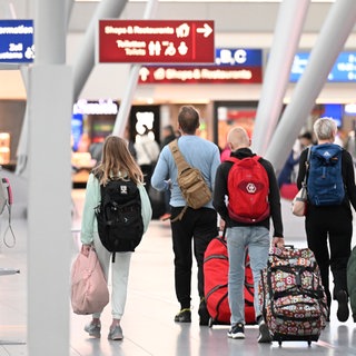 Menschen laufen mit Koffern auf einem Flughafen.