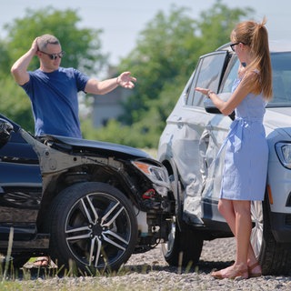 Frau und Mann stehen nach Unfall an Autos 