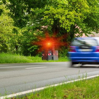 Zwei Autos fahren an Blitzer vorbei, der auslöst.