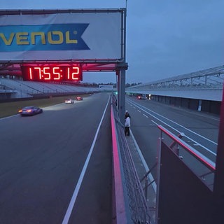 Eine Zeittafel im Vorder- und eine Rennstrecke im Hintergrund