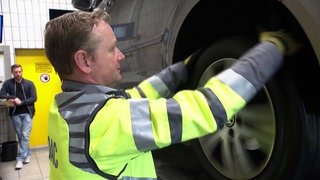 ADAC-Mitarbeiter kontrolliert in einer Werkstatt einen Autoreifen