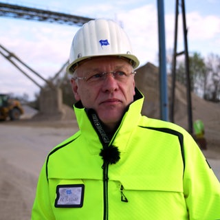 Heinz Schlecht ist Betriebsleiter des Kieswerks Meißenheim. Er trägt eine gelbe Schutzjacke und einen weißen Helm.