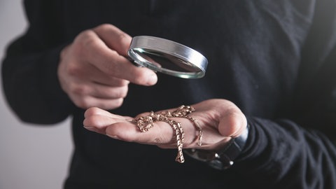 Schmuck wird durch eine Lupe betrachtet