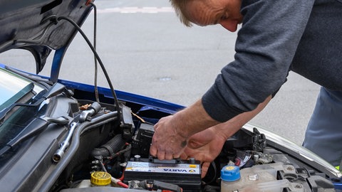 Ein Mann arbeitet an einer Autobatterie | Extreme Temperaturen: So lebt eure Autobatterie länger  Autobatterie im Winter
