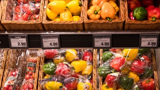 In Plastik verpackte Paprika liegen in einem Supermarkt neben losen Paprika zum Verkauf aus. 