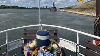 Eine Urne wird auf einem Fluss zur Beisetzung transportiert.