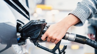 Eine Frau betankt ihr Auto: Es gibt Tipps, wo man wann am günstigsten Tanken kann.