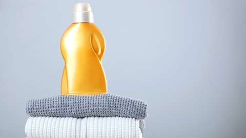 Waschmittel steht auf Stapel Wollpullovern