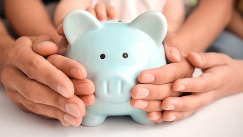 Eltern und Kind legen Hände um Sparschwein