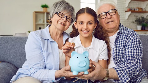 Enkelin mit Oma und Opa und Sparschwein