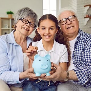 Enkelin mit Oma und Opa und Sparschwein