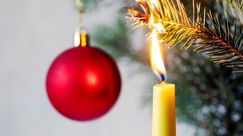 Kerze brennt am Weihnachtsbaum