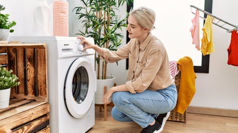 Frau hockt vor der Waschmaschine