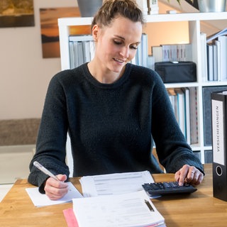 Eine junge Frau lächelt über ihre Steuererklärung | Warum ihr zum Jahresende schon an die Steuererklärung denken solltet