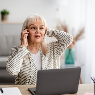 Frau telefoniert am Handy und wirkt ängstlich