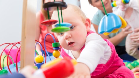 Ein Kleinkind spielt mit verschiedenen Spielzeugen. Die EU durch Vorschriften für sicheres Kinderspielzeug sorgen.