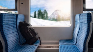 Bahnsitze mit Rucksack und Winterlandschaft im Hintergrund