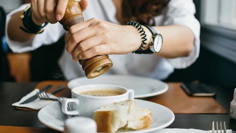 Frau würzt Suppe mit Pfeffer
