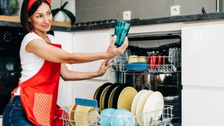 Frau hält sauberes Glas Geschirrspüler