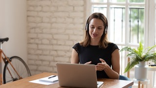 Junge Geschäftsfrau bespricht Projektdetails mit Kunden per Videoanruf.