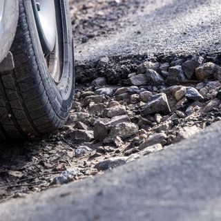 Ein Auto fährt durch ein Schlagloch | Schaden durch Schlaglöcher: Das könnt ihr tun