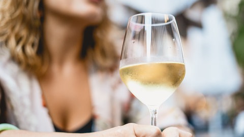 Weißwein im Glas auf dem Tisch vor einer Frau