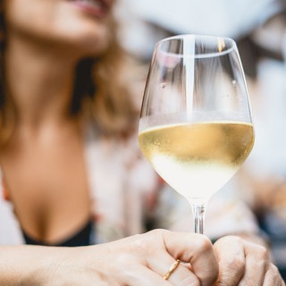 Weißwein im Glas auf dem Tisch vor einer Frau