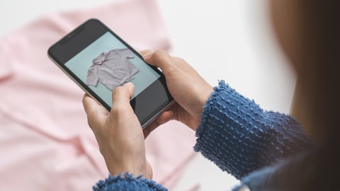 Gebrauchte Bluse wird mit dem Smartphone fotografiert